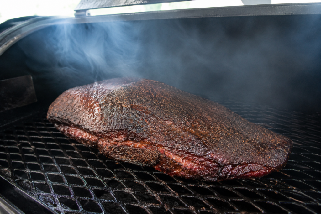Brisket nello smoker durante la cottura con fumo leggero e pulito